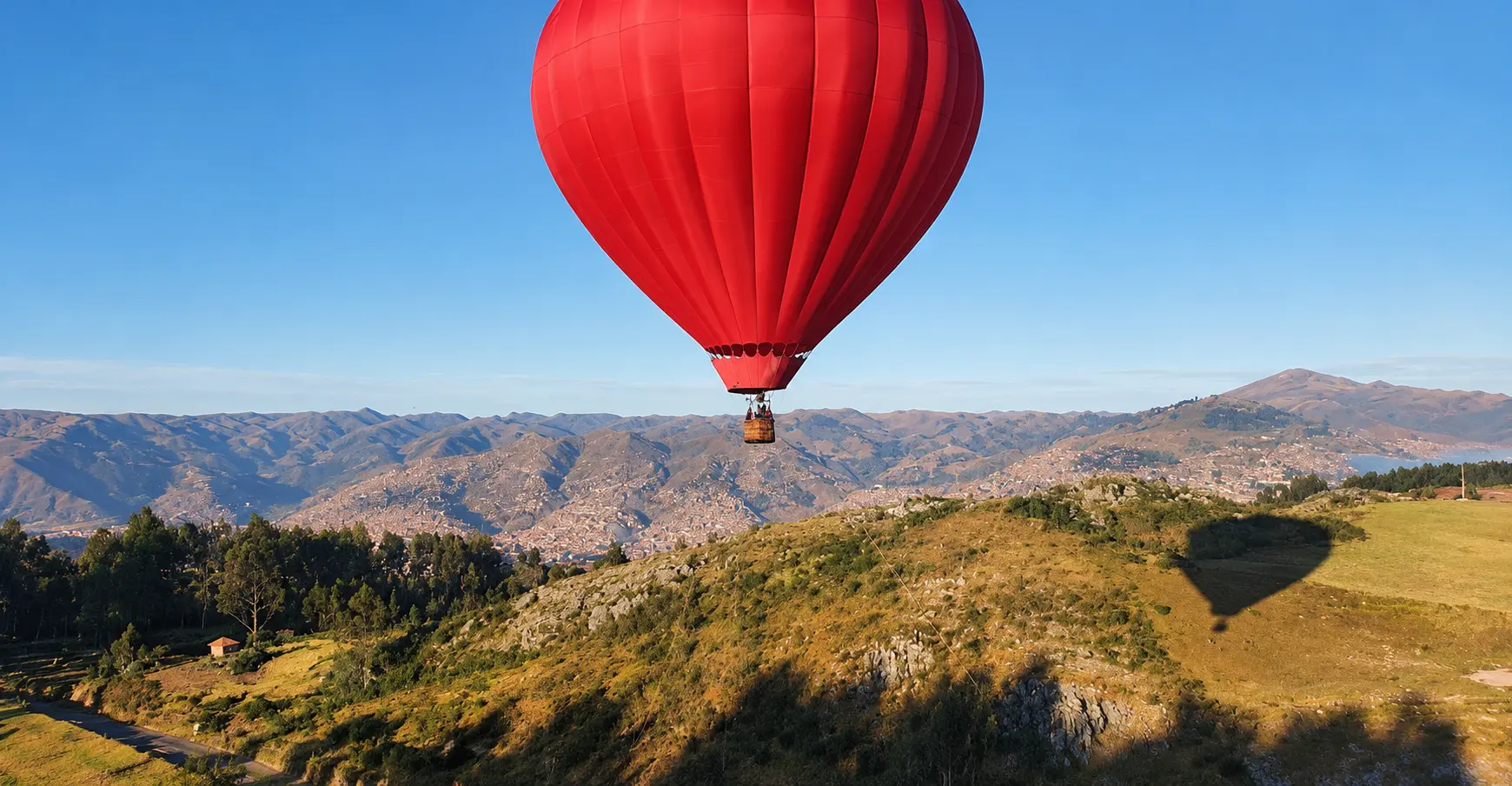 Globo aerostático rojo elevándose sobre los cerros cercanos a Cusco
